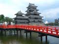 堀に架かる真っ赤な橋と国宝松本城の写真